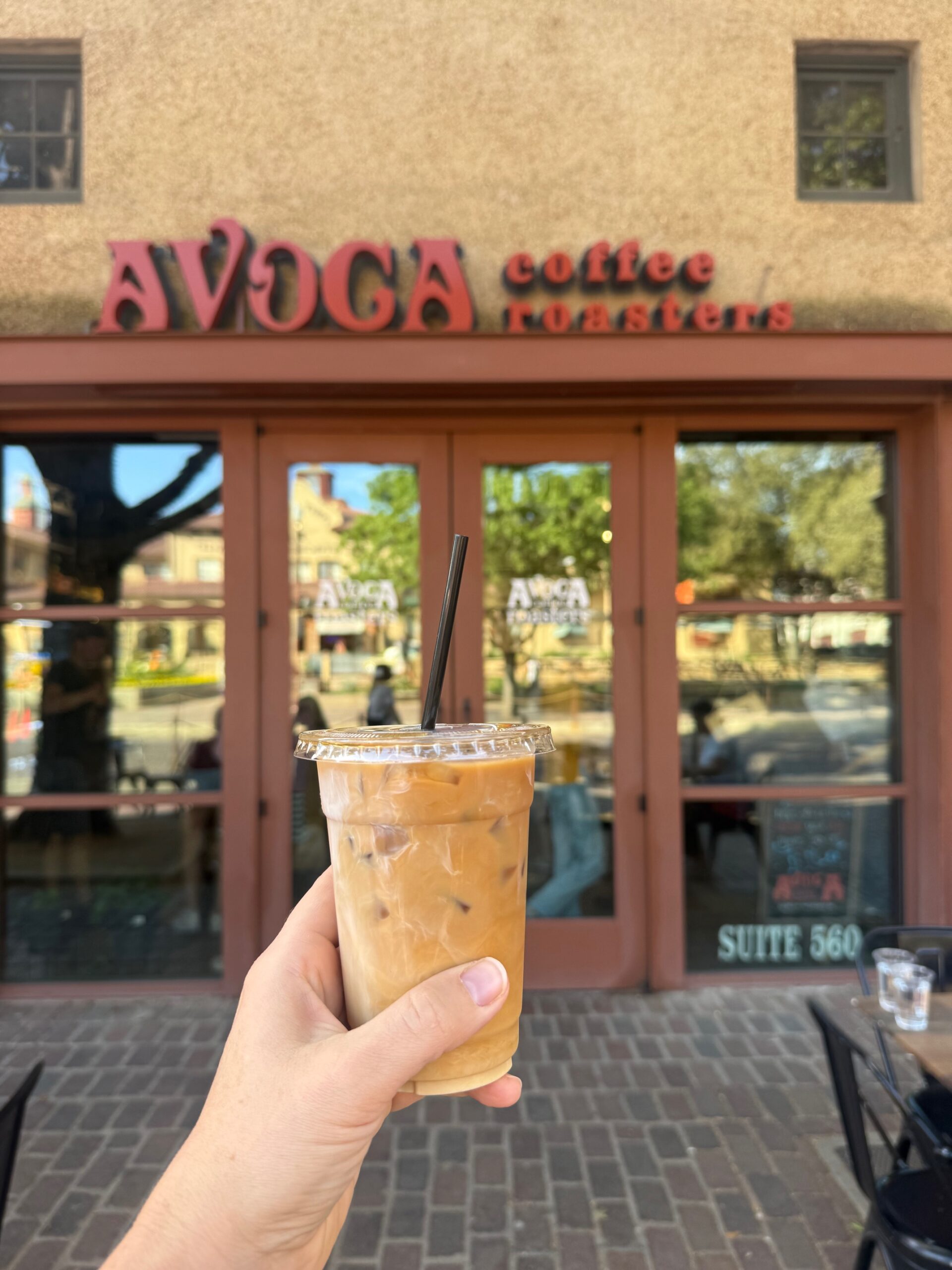 Iced latte in front of avoca coffee roasters fort worth