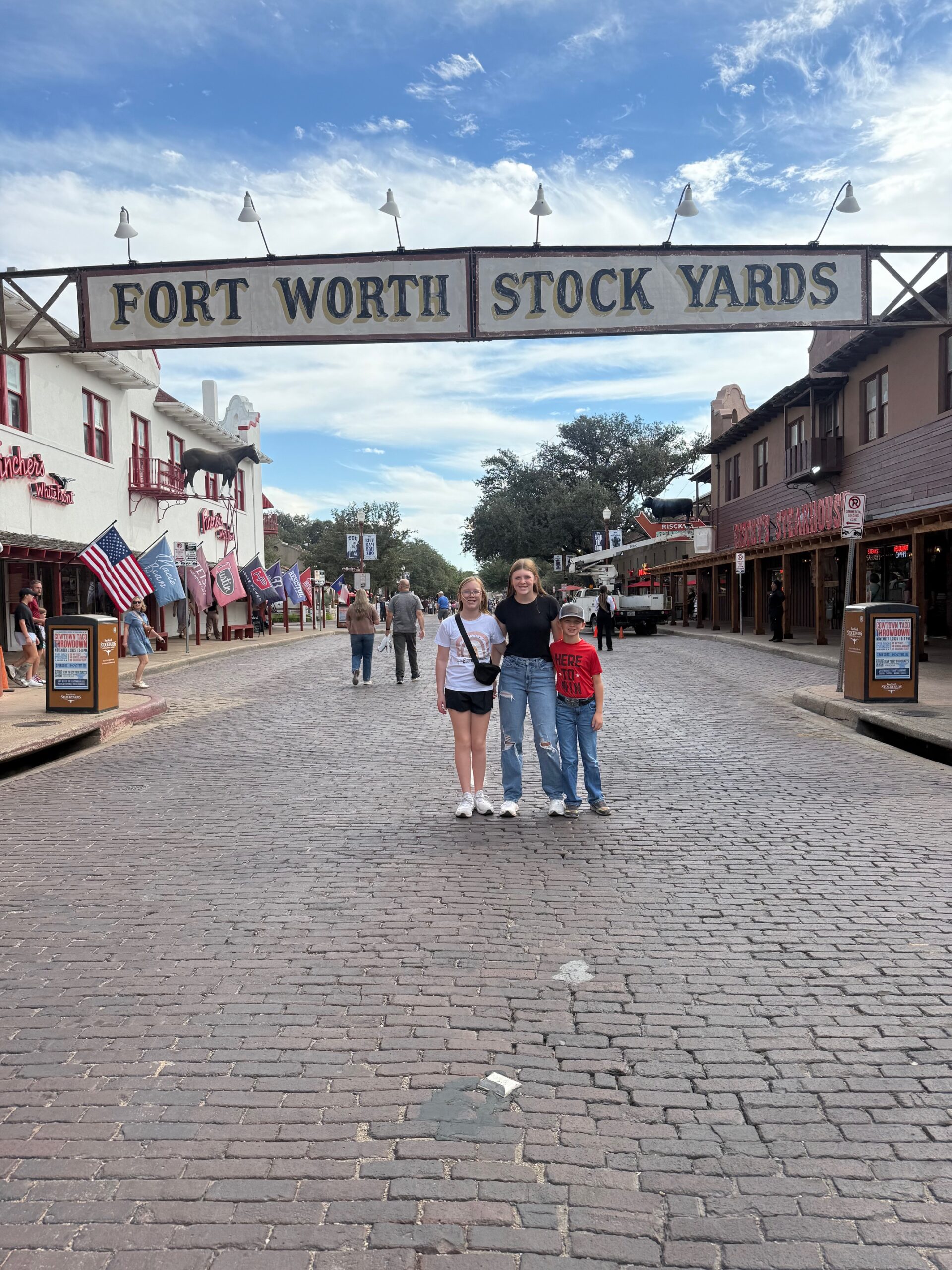 Three children in front of fort worth stockyards sign