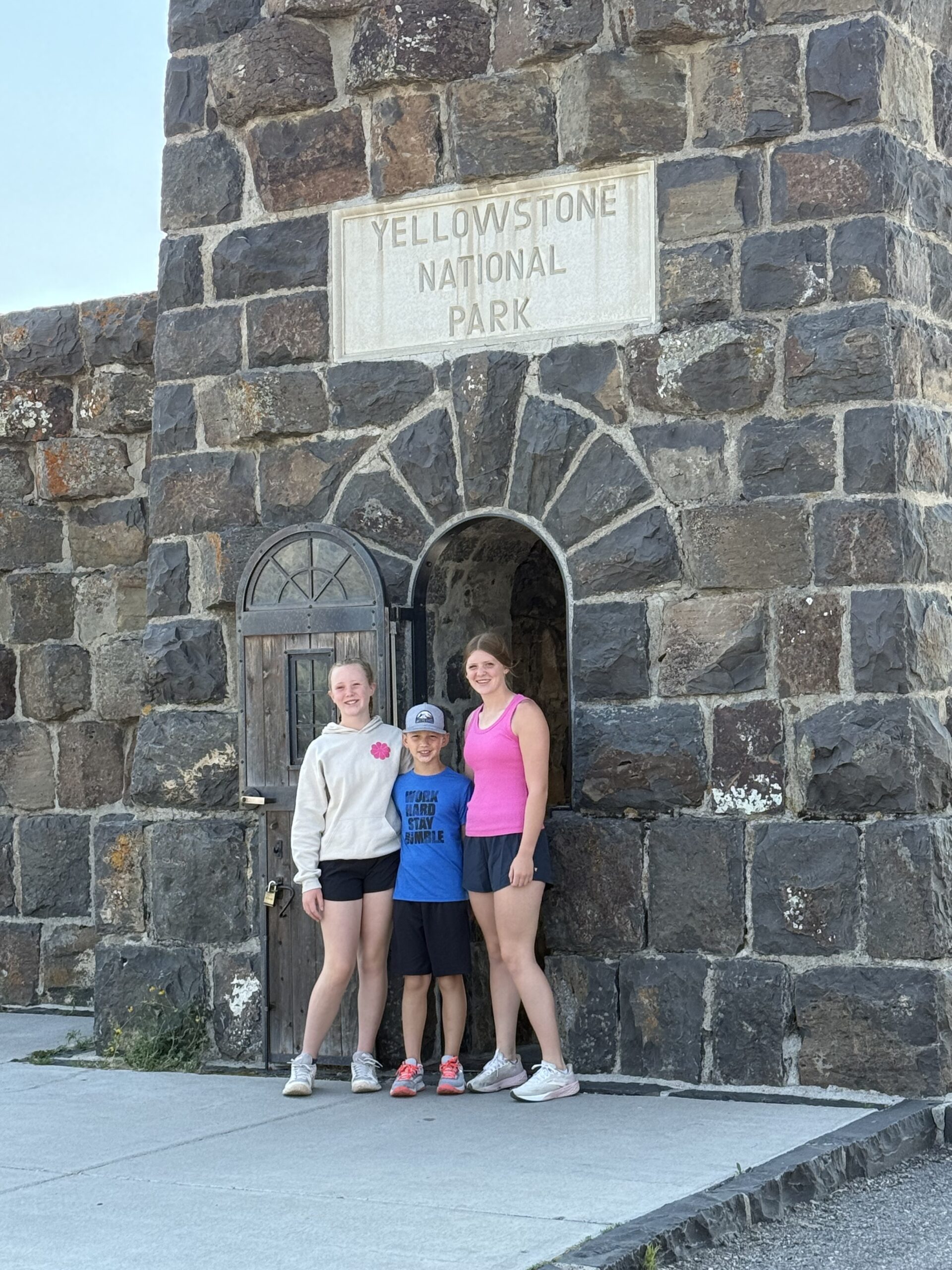 Two girls and a boy in front of Roosevelt tower going into Yellowstone National Park